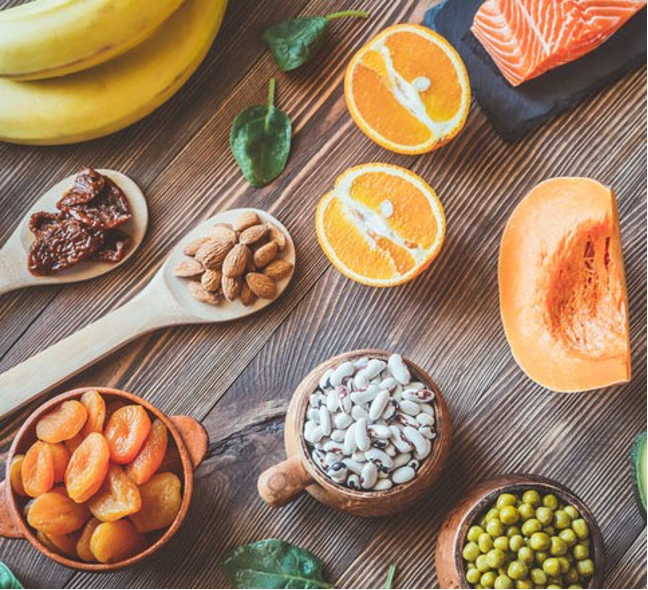 healthy foods that are high in electrolytes, especially targeting high-altitude nutrition, dried fruits, beans, salmon, bananas, nuts, on bowls and wooden spoon atop a rustic heavily grained wood surface